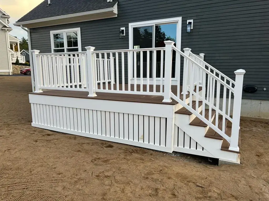 Composite deck landing with white posts and white stairs leading to lawn.
